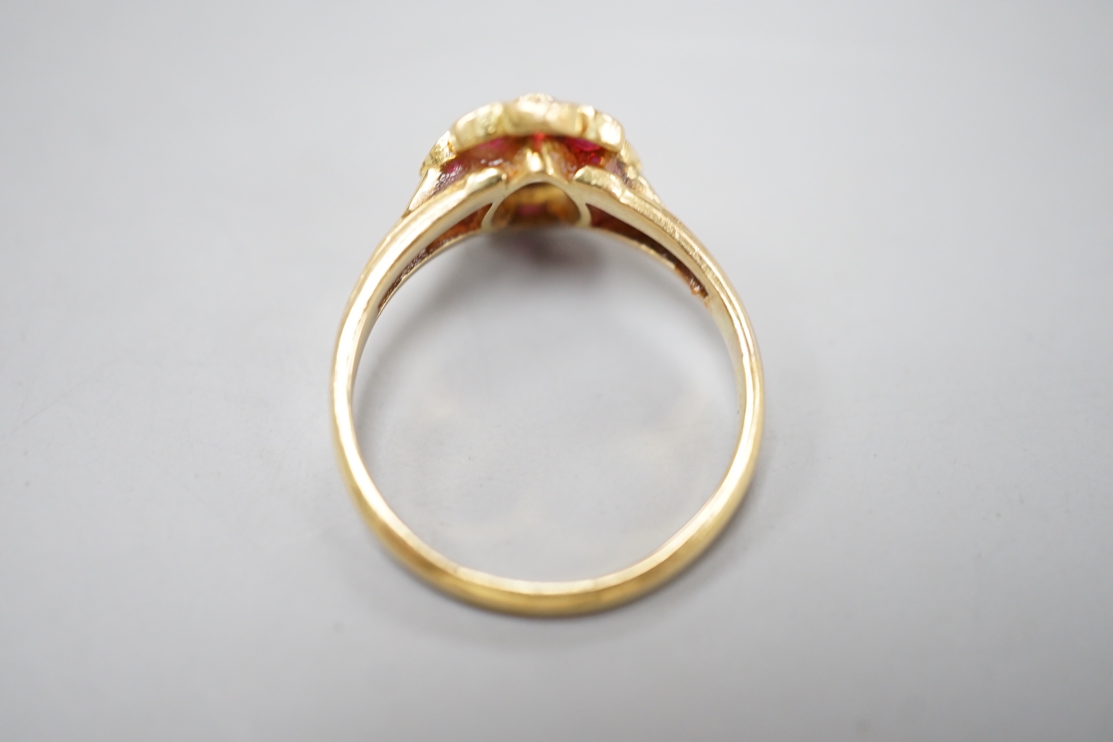 An early 20th century yellow metal and pear cut single stone diamond ring, with ruby set border, size O, gross weight 3.3 grams.